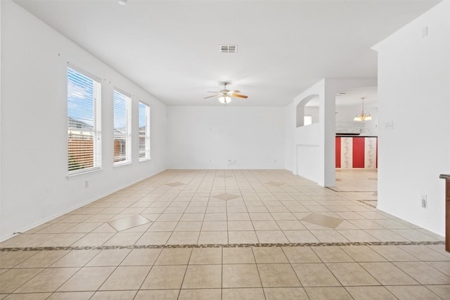 spare room featuring ceiling fan with notable chandelier, visible vents, and light tile patterned floors