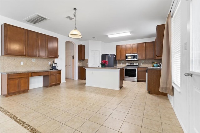 kitchen with a center island, pendant lighting, brown cabinets, visible vents, and appliances with stainless steel finishes