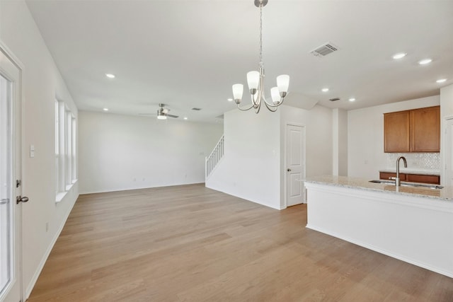 14013 Vigilance St, Manor, TX 78653 - kitchen with a ceiling fan, recessed lighting, brown cabinetry, light wood finished floors, and hanging light fixtures