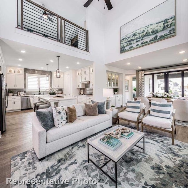 living room featuring ceiling fan, plenty of natural light, a towering ceiling, and hardwood / wood-style floors