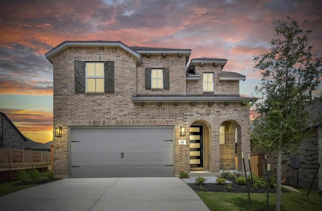 view of front of house with brick siding, an attached garage, and driveway