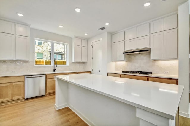 kitchen with gas cooktop, visible vents, dishwasher, under cabinet range hood, and light wood-style flooring