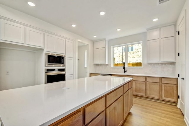 kitchen with a sink, appliances with stainless steel finishes, backsplash, and light countertops