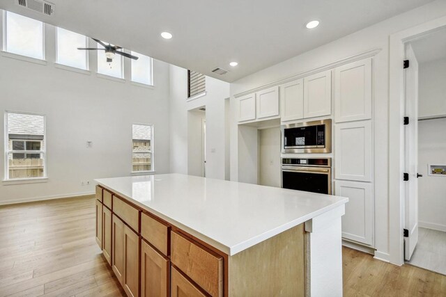 kitchen with a kitchen island, stainless steel appliances, a ceiling fan, and light wood-style flooring