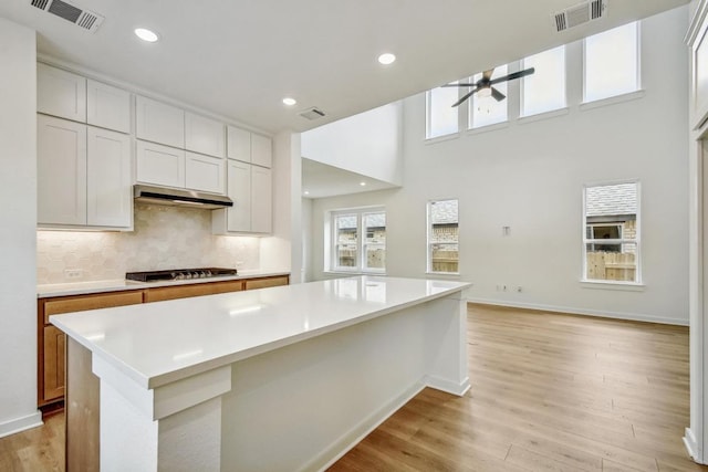 kitchen featuring light countertops, a ceiling fan, under cabinet range hood, and visible vents