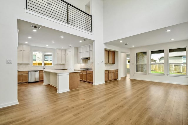 kitchen featuring visible vents, open floor plan, tasteful backsplash, light wood finished floors, and dishwasher