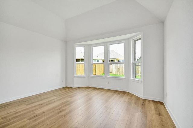 unfurnished room featuring baseboards, vaulted ceiling, and light wood-style floors