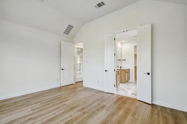 unfurnished bedroom featuring baseboards, vaulted ceiling, light wood finished floors, and visible vents