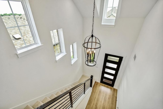doorway with light wood-type flooring, high vaulted ceiling, baseboards, an inviting chandelier, and stairs