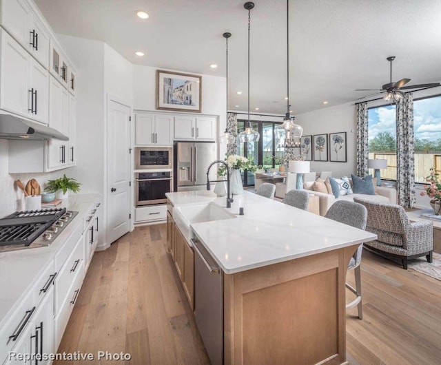 kitchen with sink, pendant lighting, a spacious island, white cabinets, and appliances with stainless steel finishes