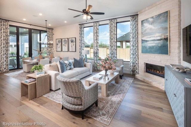 living room featuring light hardwood / wood-style floors, a stone fireplace, and plenty of natural light