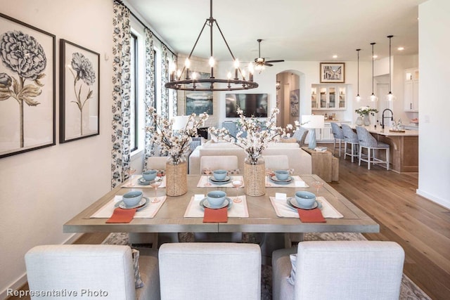 dining area with hardwood / wood-style flooring, ceiling fan with notable chandelier, and a wealth of natural light