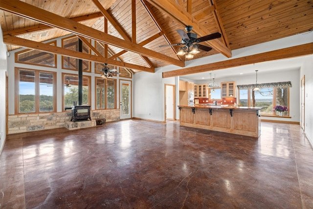 unfurnished living room featuring a wood stove, beamed ceiling, wood ceiling, and high vaulted ceiling