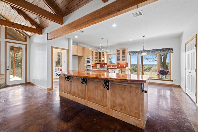 kitchen with vaulted ceiling with beams, a center island, hanging light fixtures, and wooden ceiling