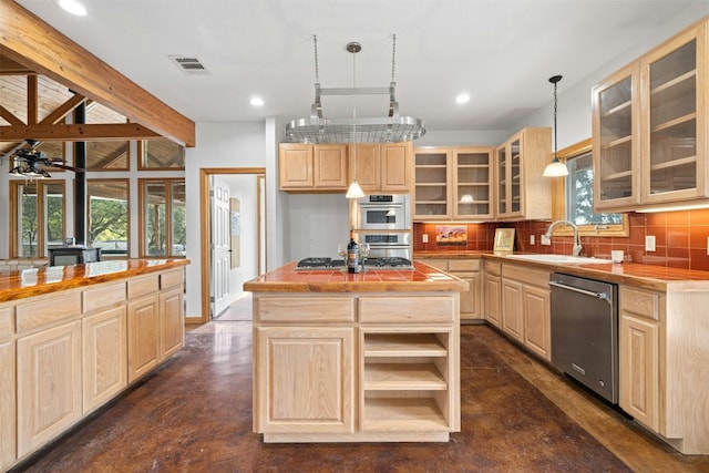 kitchen with light brown cabinetry, a kitchen island, hanging light fixtures, and appliances with stainless steel finishes