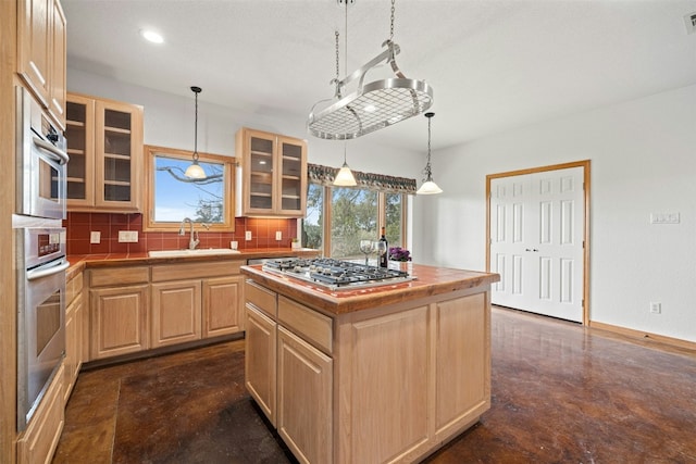 kitchen featuring sink, a center island, light brown cabinets, backsplash, and stainless steel gas stovetop