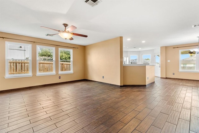 spare room featuring ceiling fan with notable chandelier