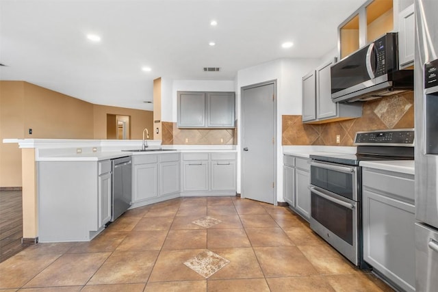 kitchen with kitchen peninsula, appliances with stainless steel finishes, gray cabinetry, sink, and light tile patterned flooring