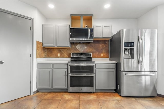 kitchen with tasteful backsplash, gray cabinets, light tile patterned floors, and appliances with stainless steel finishes