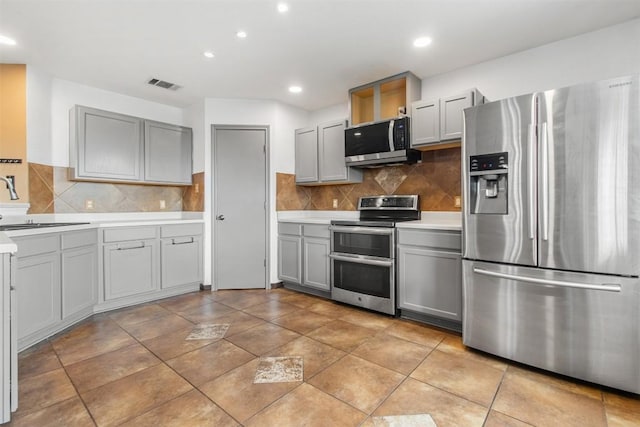 kitchen with tasteful backsplash, gray cabinetry, stainless steel appliances, sink, and light tile patterned floors