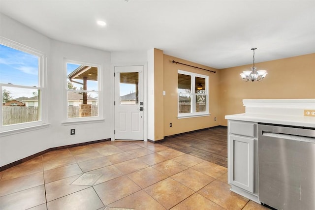 kitchen with light tile patterned floors, an inviting chandelier, stainless steel dishwasher, pendant lighting, and white cabinets