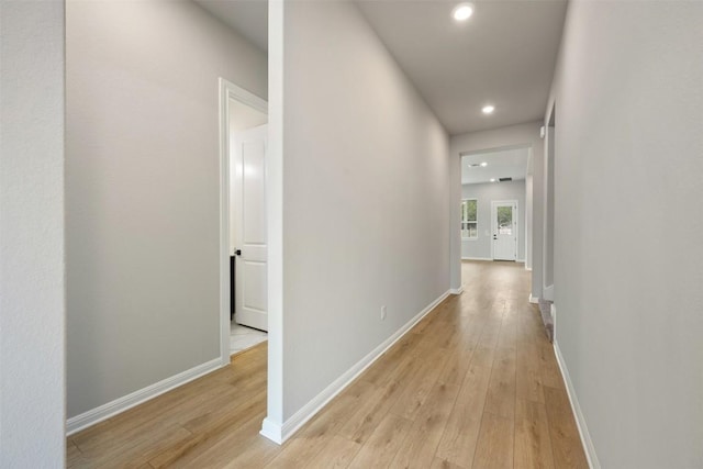 hallway with light wood finished floors, baseboards, and recessed lighting
