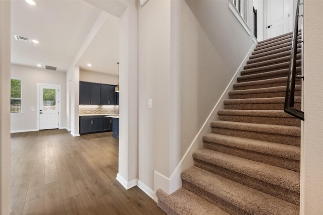 stairs featuring recessed lighting, baseboards, visible vents, and wood finished floors