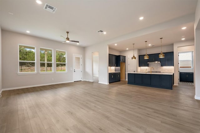 unfurnished living room with visible vents, baseboards, and ceiling fan