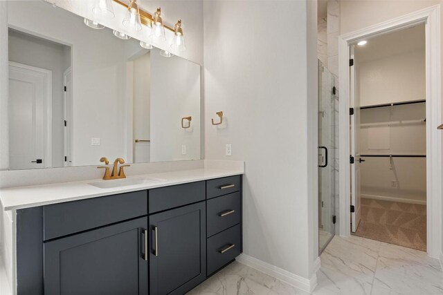 bathroom with marble finish floor, vanity, a stall shower, a walk in closet, and baseboards