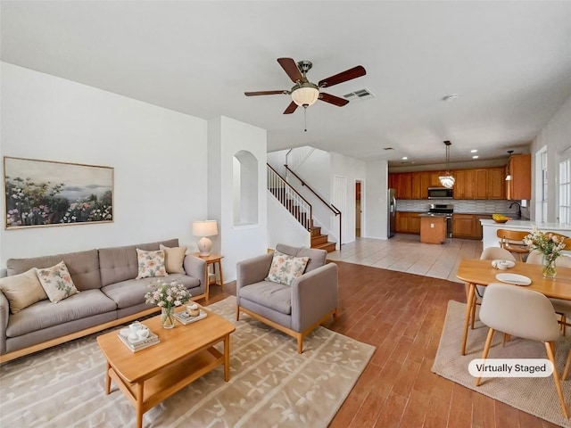 living room featuring ceiling fan, sink, and light hardwood / wood-style flooring