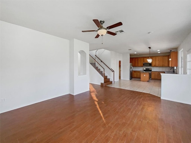 unfurnished living room featuring ceiling fan and light hardwood / wood-style flooring