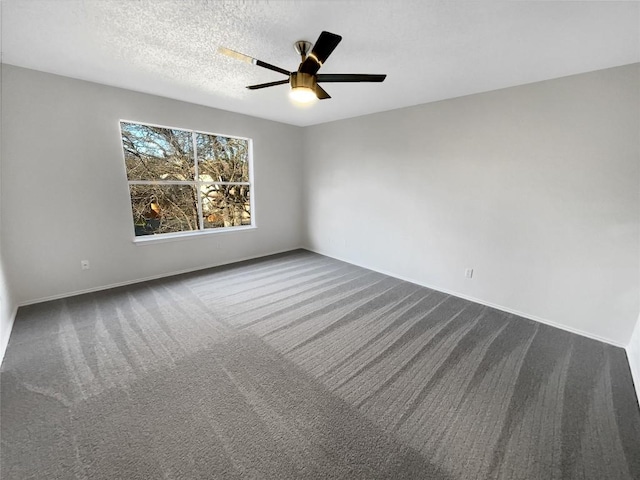 empty room featuring dark colored carpet, ceiling fan, and a textured ceiling