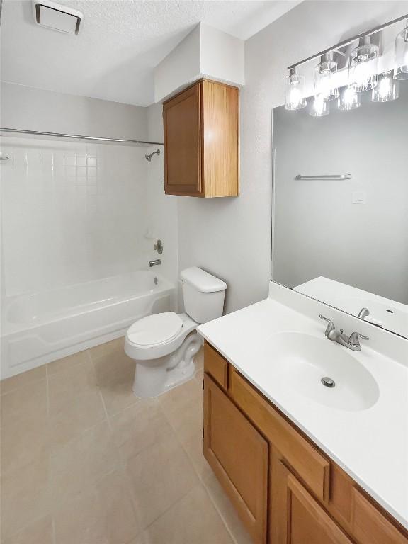 full bathroom with vanity, shower / washtub combination, tile patterned flooring, toilet, and a textured ceiling