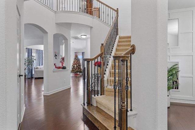 staircase with hardwood / wood-style flooring and a high ceiling