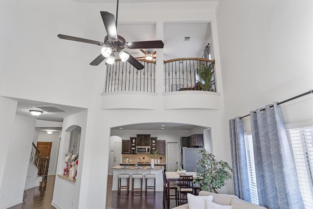 living room with a high ceiling, dark hardwood / wood-style flooring, and ceiling fan