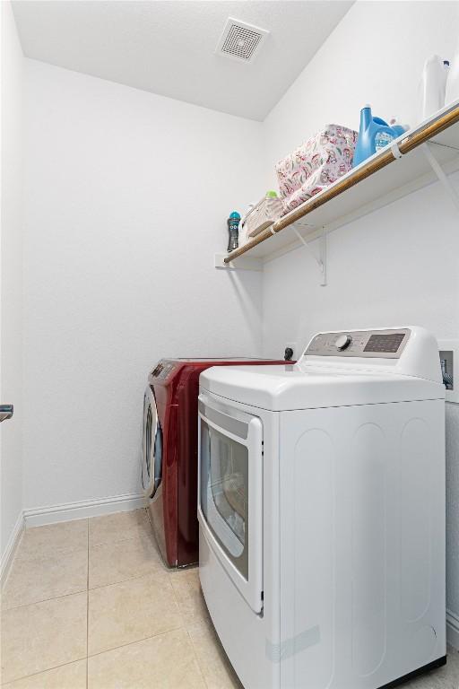 clothes washing area featuring washer and dryer and light tile patterned floors