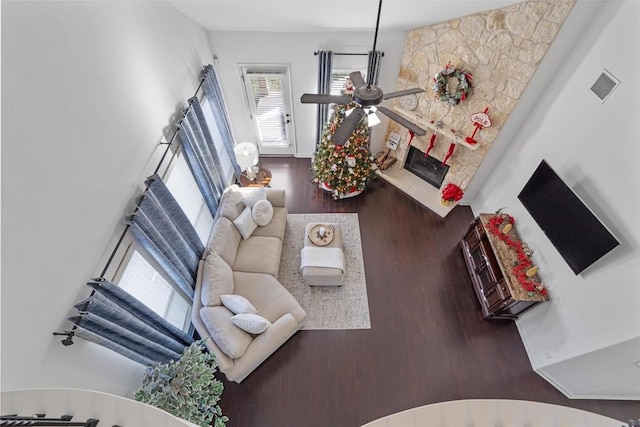 living room with a stone fireplace, ceiling fan, and hardwood / wood-style flooring