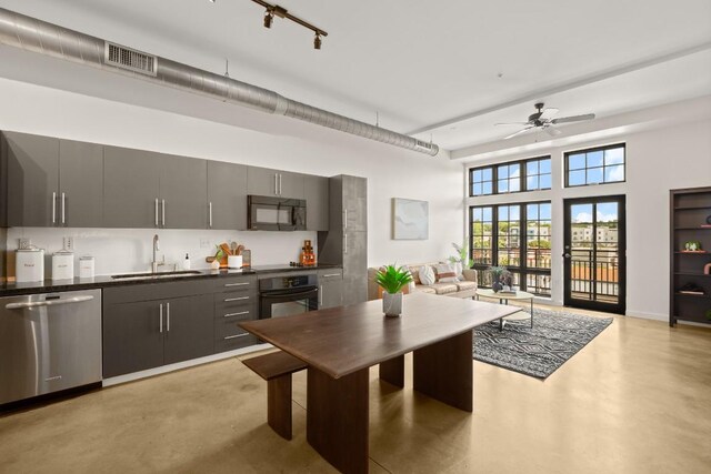 kitchen with dishwasher, oven, sink, ceiling fan, and a towering ceiling