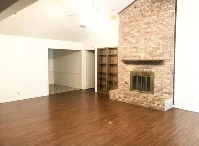 unfurnished living room featuring lofted ceiling, dark hardwood / wood-style floors, and a brick fireplace