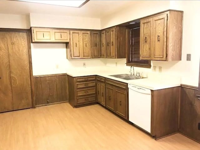 kitchen featuring wood walls, white dishwasher, light hardwood / wood-style floors, and sink