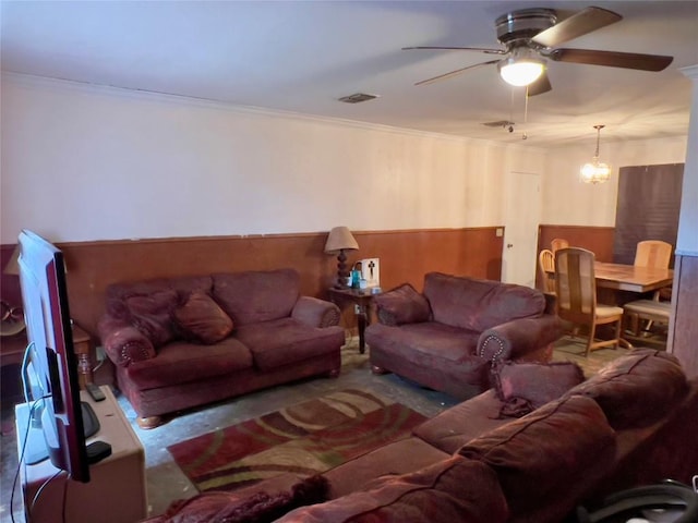 living room with ceiling fan with notable chandelier and ornamental molding