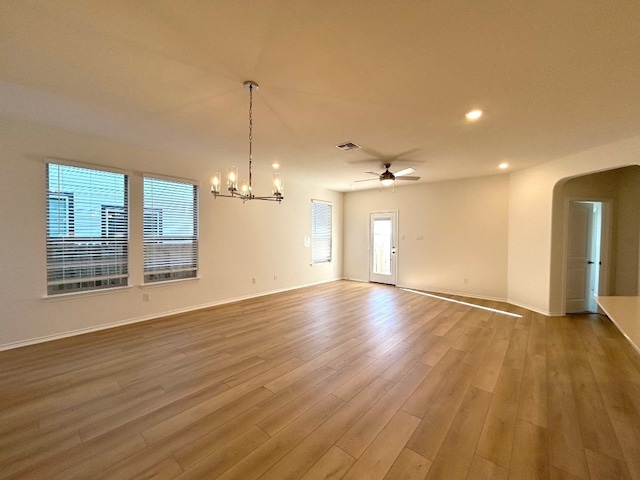 empty room with wood-type flooring and ceiling fan with notable chandelier