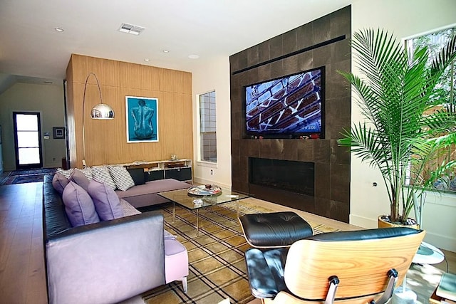 living room with a tiled fireplace and light hardwood / wood-style floors