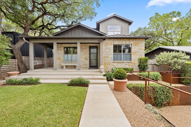 1005 Jewell St, Austin, TX 78704 - view of front of house with stone siding, covered porch, board and batten siding, and a standing seam roof