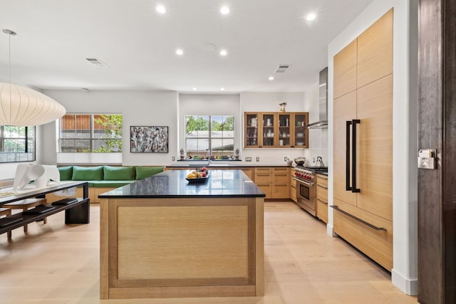 1005 Jewell St, Austin, TX 78704 - kitchen with premium appliances, dark countertops, recessed lighting, a kitchen island, and wall chimney range hood