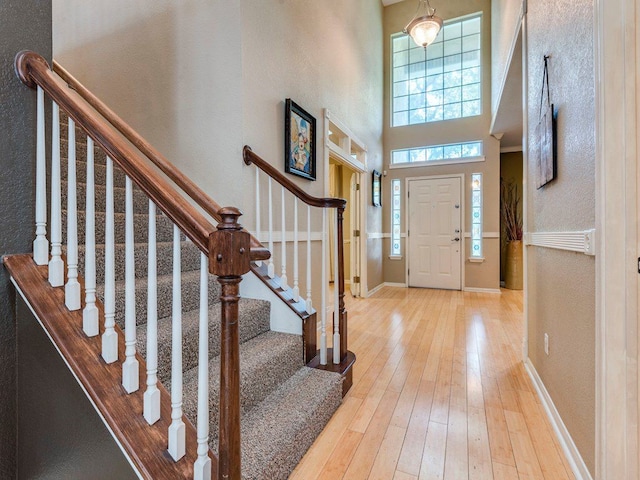 foyer entrance featuring light wood-type flooring, a high ceiling, and a chandelier