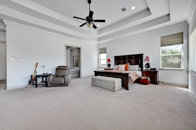 carpeted bedroom with multiple windows, a tray ceiling, ceiling fan, and ornamental molding