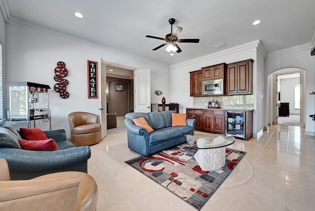 living room with ceiling fan, light tile patterned floors, beverage cooler, and ornamental molding