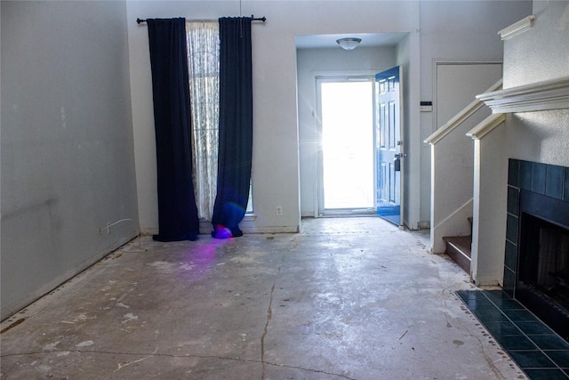 foyer entrance featuring a tile fireplace and concrete flooring