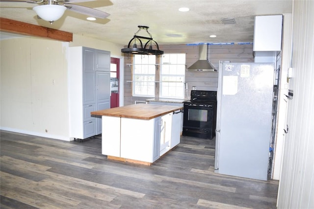 kitchen featuring wooden counters, black range with electric stovetop, wall chimney exhaust hood, decorative light fixtures, and white fridge